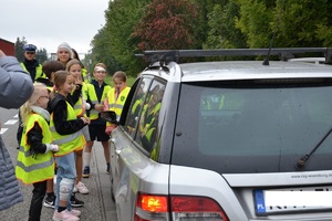 Dzieci w kamizelkach odblaskowych oraz policjant przy pojeździe